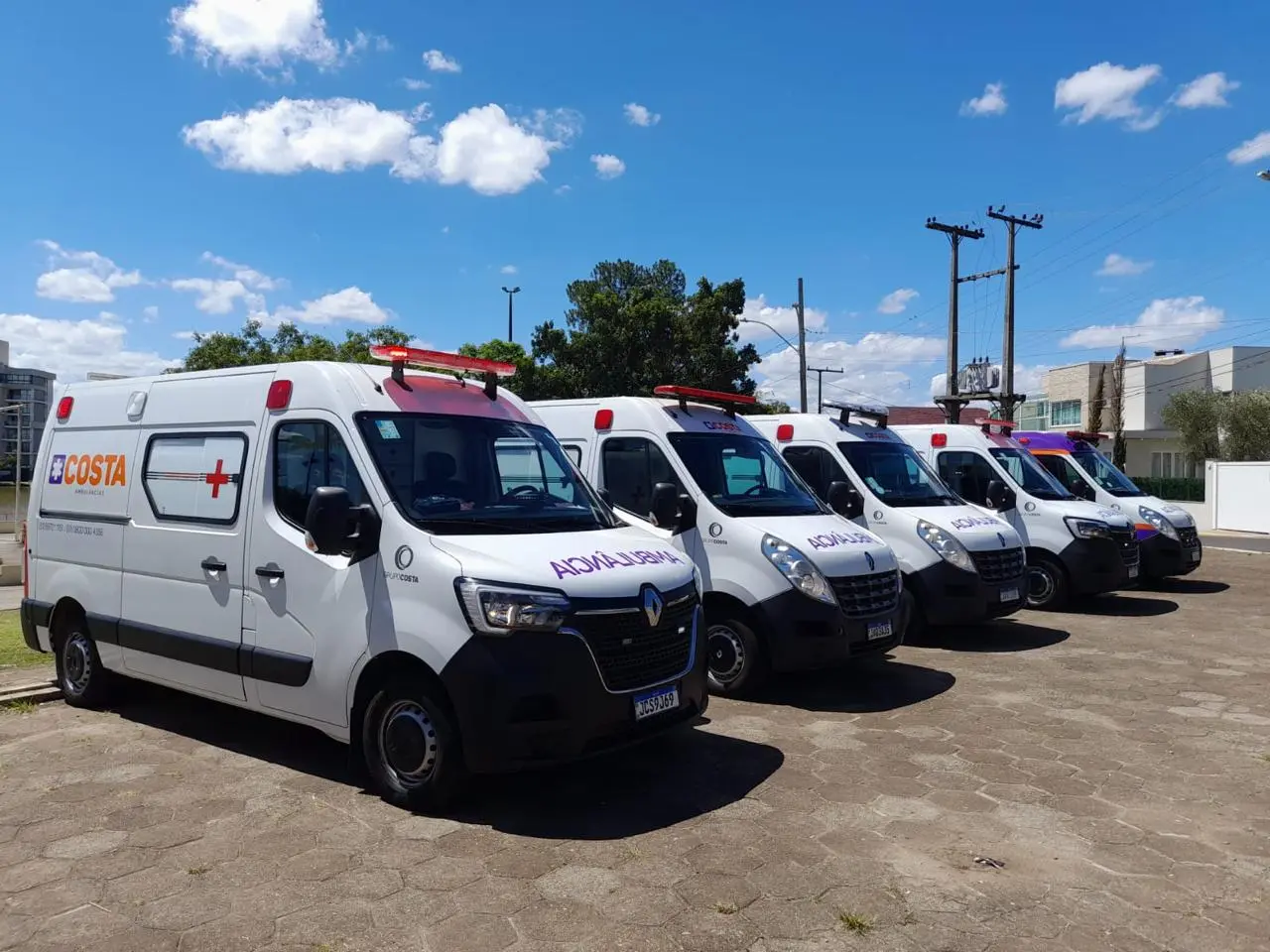 Frota de ambulâncias da Costa enfileirada em dia de sol.